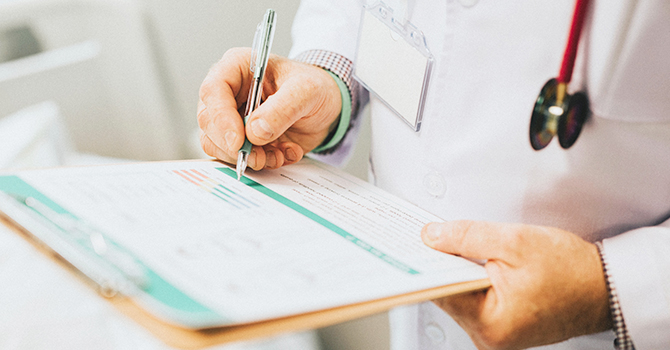 A doctor writing on a clip board.