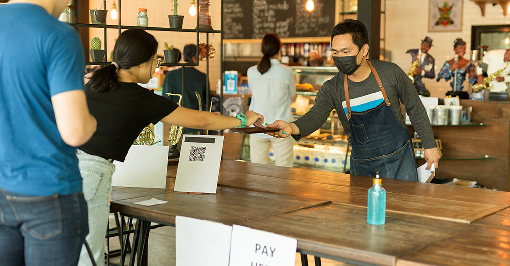 A coffee shop with patrons and employees wearing masks.