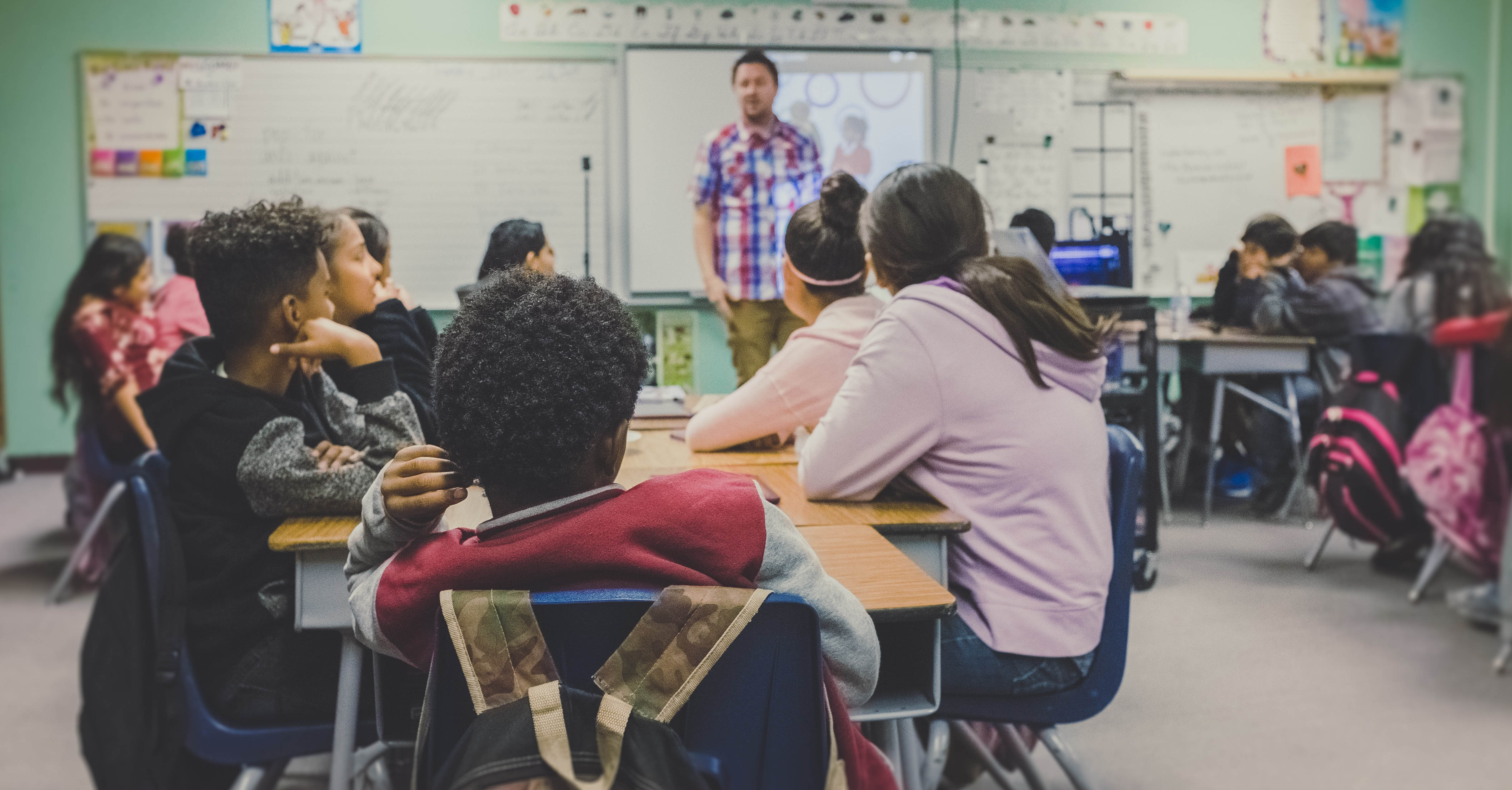 A group of middle-school aged children sitting in a classroom.