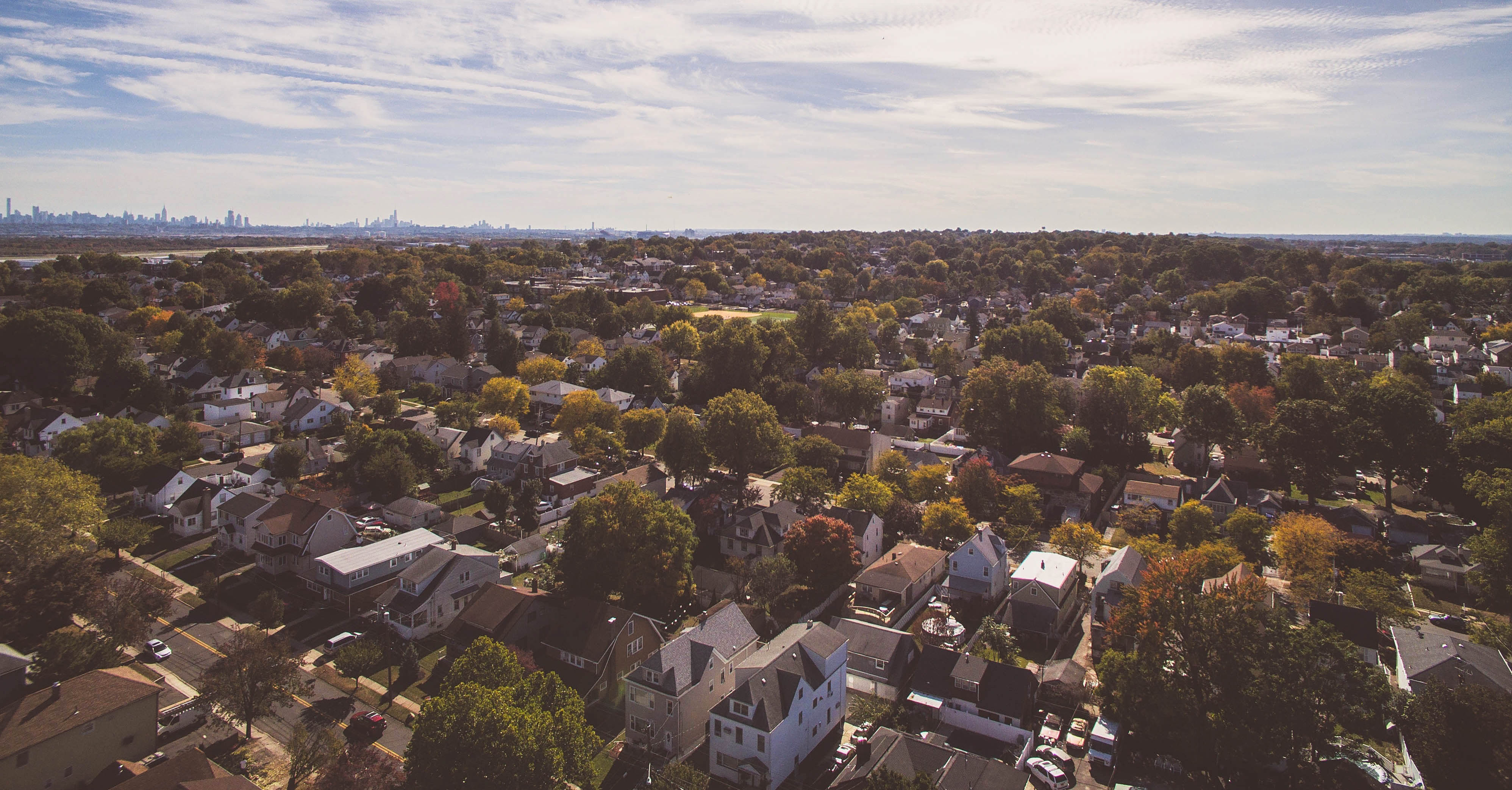 A sky view image of a neighborhood with multi-story homes and trees.