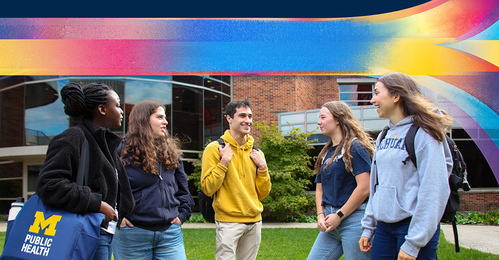 University of Michigan Public Health students gather outside under a colorful abstract banner