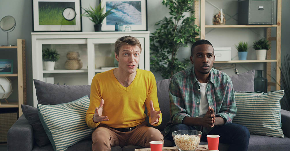 Two people sitting on a couch watching television.