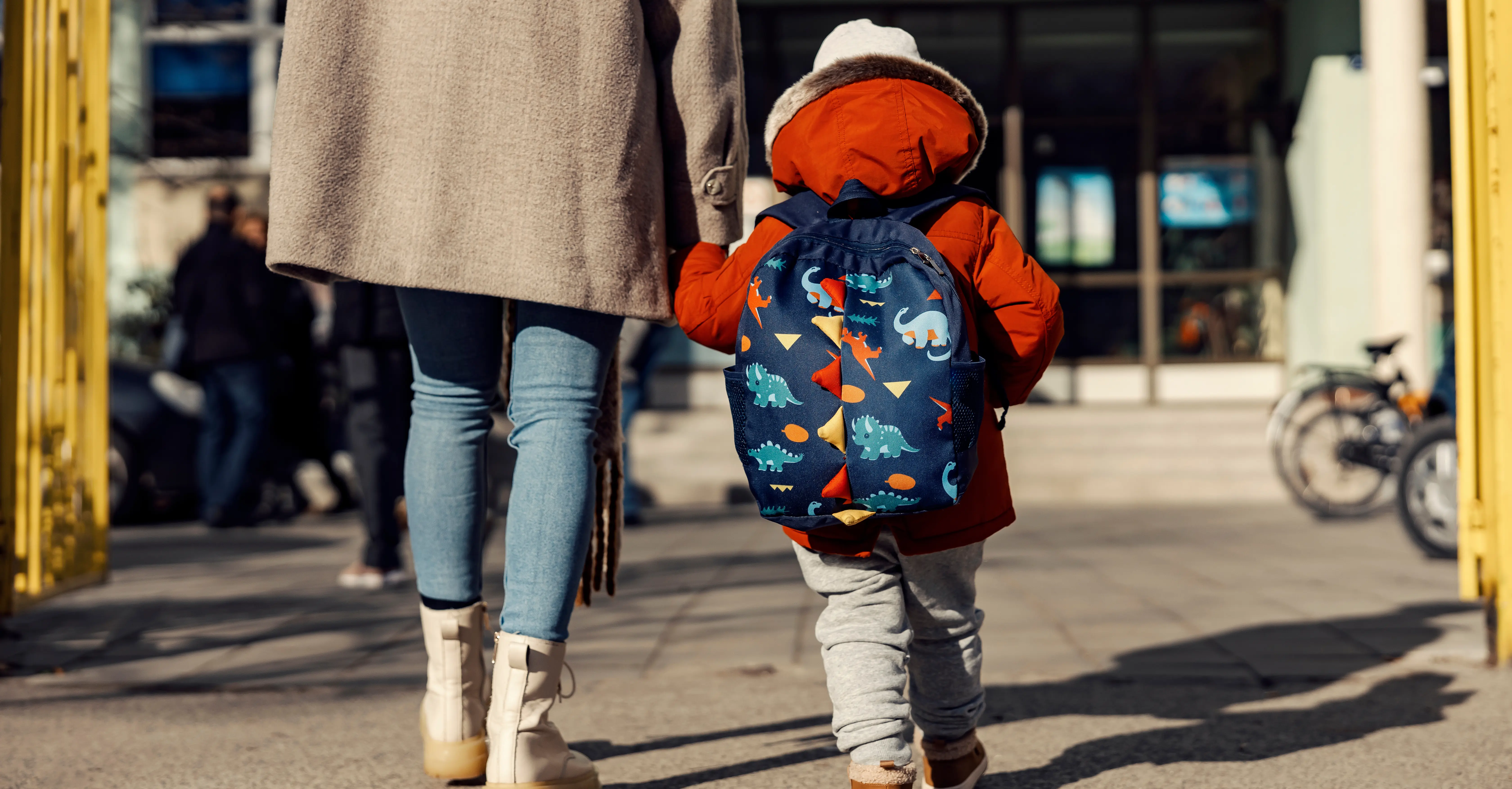 A woman walks toward a school with a small child. 