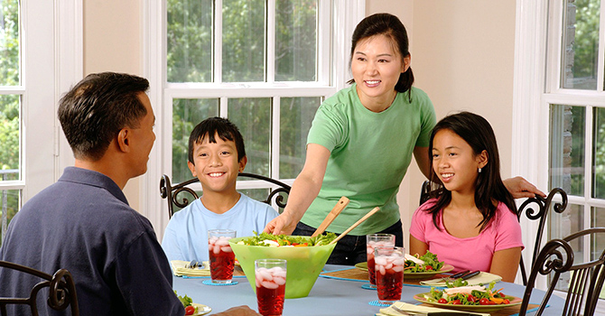 family sitting at table, getting ready to eat dinner