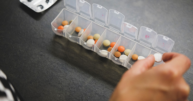 woman grabbing pill from pill box