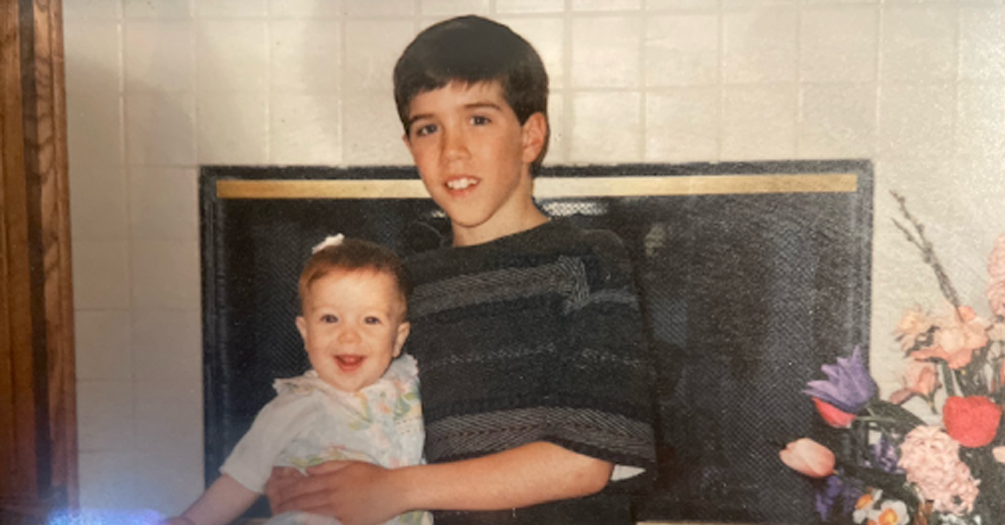 Photo: Annalisa, a young toddler, and Zachary, an elementary-aged boy, sitting in front of the fireplace at their family home.