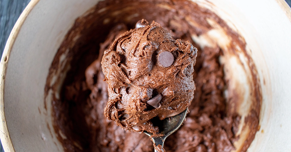 Chocolate cookie dough with chocolate chips in a mixing bowl