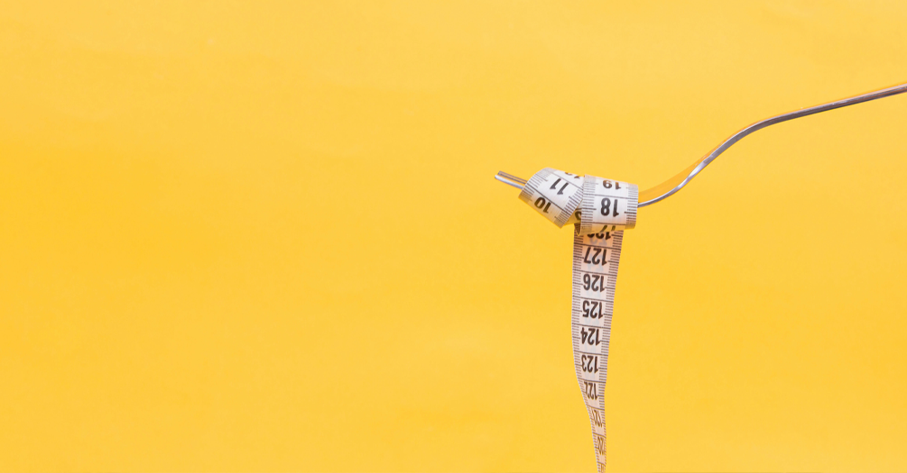 A tape measure wrapped around a fork over a yellow background